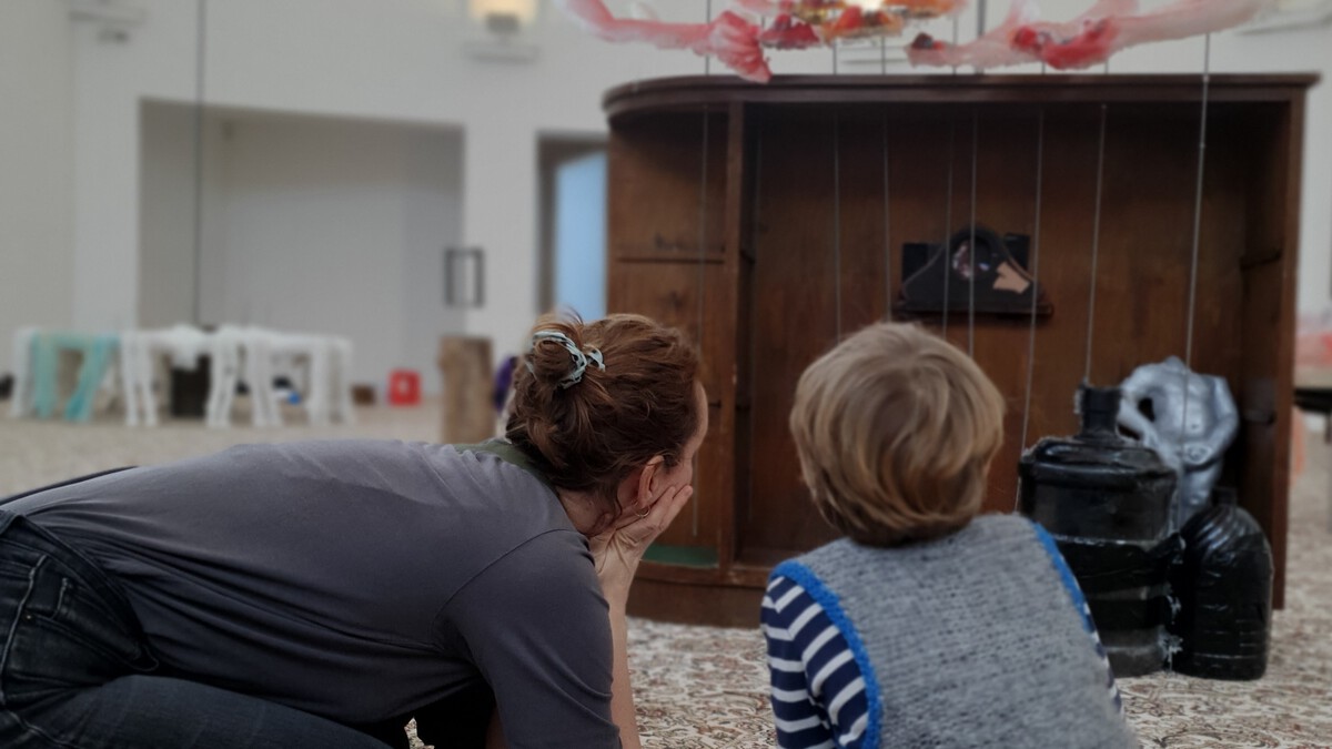 Kind schaut mit Mutter ein Werk von Rebecca Ackroyd an. Sie sind von hinten fotografiert und knien auf dem Boden. 
